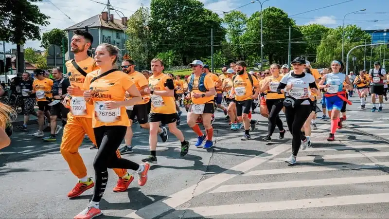 Difference Between Sneakers and Running Shoes. the picture shows men's and women's wearing yellow shirts running on road