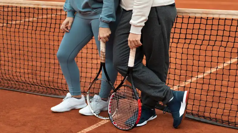 The Difference Between Sneakers and Tennis Shoes. the picture shows friends standing in tennis court wearing tennis shoes.